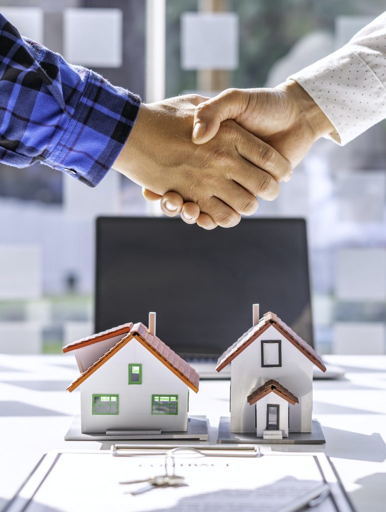 Real estate agents and clients shake hands and deliver the keys. After signing the contract to purch